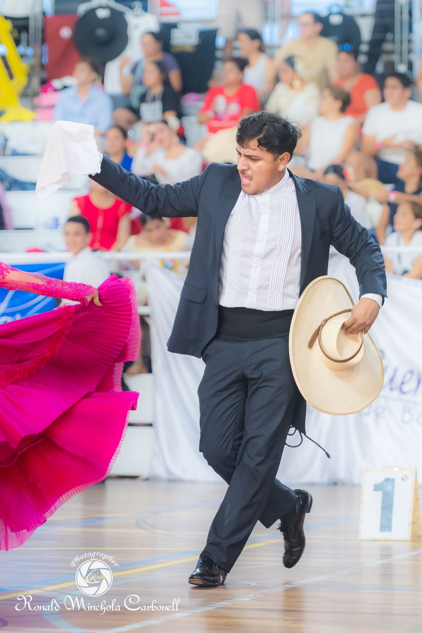 Bailarín de marinera norteña con traje negro, pañuelo y sombrero en la mano